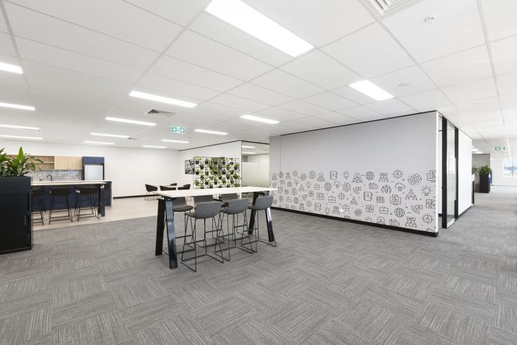 A view of an office area with a high table and stools, near a wall with a creative doodle design.