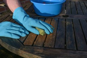 hands,in,blue,rubber,gloves,cleaning,a,weathered,wooden,garden